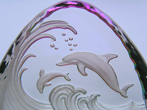 Crystal Figurine with Carved Frosted Double Dolphins in a Colorful Luminescent Sea. Enlarged to show detail. Actual size is 2.5 Inches Wide, 2.25 Inches Tall.